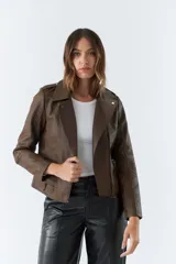 Campera marrón de cuero sintético, estilo motociclista, con cuello solapa, cierre asimétrico, bolsillos con cierre y detalles de costuras en los hombros y mangas.