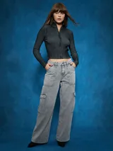 Jean cargo de tiro alto, color gris lavado, con corte ancho y pierna acampanada. Presenta bolsillos cargo grandes en los muslos y costuras marcadas.