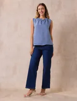 Blusa celeste sin mangas en crepe con cuello a la base con frunce, apertura ojal y botón.