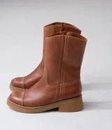 Bota de cuero vacuno color marrón, con caña media, suela de caucho y punta redonda.