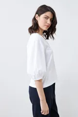 Remera blanca con escote en V y mangas balloon 3/4.