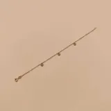 Pulsera de oro amarillo 10K con cadena fina y cuatro dijes pequeños con forma de corazón colgantes.