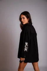 Camisa celeste de corte clásico, con botones frontales y bordados florales en las mangas.