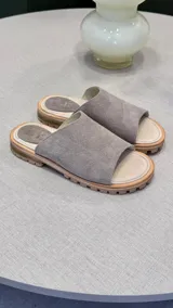 Sandalias tipo chinelas color gris topo, con capellada ancha de gamuza, plantilla de cuero y suela de goma.