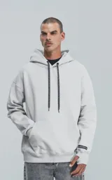Hoodie gris de frisa premium con capucha ajustable, corte oversize, cintura y puños elastizados.