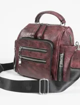 Mochila bandolera color marrón con múltiples bolsillos con cierre plateado.