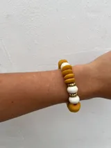 Set de tres pulseras elásticas con cuentas de madera en colores celeste, negro y rosa, con detalles de cuentas doradas y cuentas color crema.