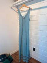 Vestido largo celeste de algodón con escote en V y breteles finos. Presenta bordado geométrico en escote y ruedo. Tiene lazo ajustable en el busto.