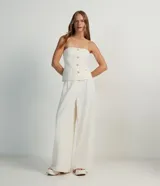 Blusa estilo corset color blanco, con escote recto, sin mangas, abotonado frontal y solapas aplicadas.