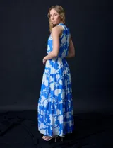 Vestido largo de gasa con estampado floral en tonos celeste y blanco. Tiene escote halter, cintura elastizada con lazo de ajuste, abertura en la espalda con botones y forro interno.