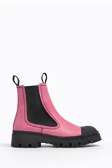 Botín Chelsea de cuero color rosa con puntera y suela track color negro. Cuenta con elásticos laterales negros y tiradores en la parte trasera.