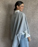 Ruana tejida en lana color gris claro, de corte amplio y diseño abierto.
