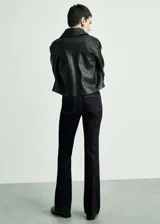 Pantalón de jean de tiro medio, color azul oscuro, con diseño acampanado y cinco bolsillos.