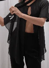 Capa corta color verde esmeralda de gasa transparente, con cuello redondo y abertura frontal con cierre de botón.