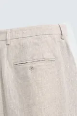 Pantalón de vestir color marrón claro, confeccionado en lino, de corte recto, con bolsillos laterales y traseros.