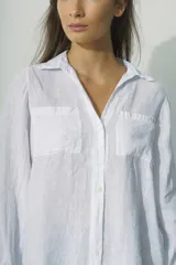 Camisa de manga larga con cuello camisero y cierre frontal con botones. Diseño a rayas verticales color beige y blanco, con dos bolsillos de parche en el pecho.