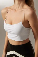 Top cropped blanco de nylon, liso y al cuerpo con tirantes finos.