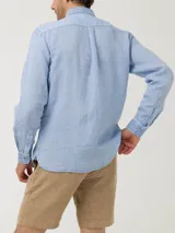 Camisa de lino color verde oliva, con cuello camisero, teñida en prenda. Tiene un bolsillo en el pecho con bordado al tono. De manga larga y calce regular.