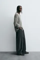 Sweater gris de punto con cuello en V, manga larga y terminaciones irregulares con efecto desgastado.