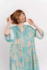 Vestido largo azul con estampado floral en tonos beige, confeccionado en viscosa. Presenta escote en V, botonadura completa en el frente y mangas largas con volados.