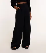 Pantalón de vestir negro, de corte recto, con bolsillos laterales y traseros. Se ajusta a la cintura con cinturón de cuero marrón.