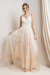 Vestido largo de fiesta color champagne con breteles finos, escote en V cruzado y falda amplia con tajo lateral. Todo el vestido está cubierto de glitter plateado.