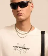 Remera de corte relaxed, color crema, con cuello redondo y mangas cortas. Presenta un estampado en la espalda con un ángel y la frase "Rule Breaker".