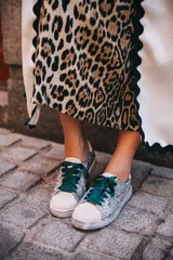 Zapatillas urbanas plateadas con glitter, puntera y talón en cuero blanco, cordones de raso verde esmeralda y suela blanca.