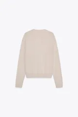 Chaqueta color crema de punto con lana, cuello redondo, manga larga y cierre frontal con botones.