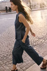 Pantalón culotte azul de lino, tiro alto, con bolsillos delanteros y traseros. Pierna ancha y corta. Cierre frontal con cremallera y botón.