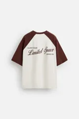 Camiseta blanca con mangas cortas marrones tipo ranglán, cuello redondo y estampado con la frase "Inner Peace" en marrón.