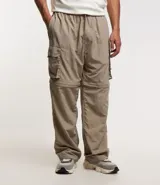 Pantalón paper touch color verde militar, con bolsillos laterales, cintura elástica y cordón de ajuste. Se convierte en bermuda gracias a un cierre a la altura de la rodilla.