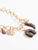 Collar plateado de cadena gruesa con dijes colgantes de estrella, corazón, herradura y cuerno.