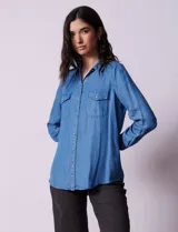 Camisa celeste de lyocell, marca Zac & Rachel. Cuello con solapa, abertura central con botones y bolsillos delanteros.