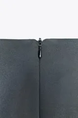 Falda midi gris de satén con drapeado frontal, abertura lateral y aplique dorado.