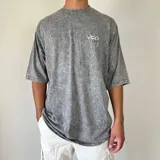 Remera gris con efecto gastado y estampado en la espalda con diseño abstracto en tonos verdes y blancos.