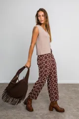 Pantalón marrón chocolate con estampa geométrica en tonos crudo, de tiro medio, corte recto, con bolsillos laterales y cintura con elástico en la parte trasera.