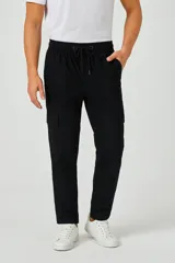 Pantalón cargo negro de corte holgado, con cintura elástica ajustable con cordón, bolsillos laterales y bolsillos tipo parche con solapa en los muslos.