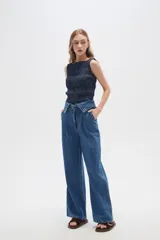 Pantalón jean de tiro alto color azul, con pinzas en la cintura, corte ancho y cierre frontal con botón y cremallera.