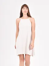 Vestido corto color crudo, de corte recto y breteles finos.