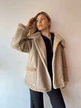 Campera gamulan color beige con interior de piel sintética, cuello solapa y cierre con botones a presión.