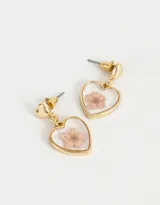 Aros colgantes dorados con forma de corazón y flor prensada en el interior.