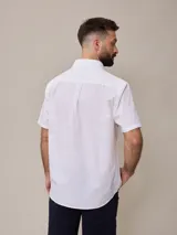 Camisa de algodón blanca de manga corta, con cuello abotonado y botones frontales.