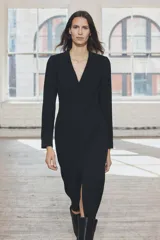 Vestido midi negro de escote pico y manga larga con hombreras. Tiene falsos bolsillos de vivo en el delantero y cierre en la espalda con cremallera oculta.