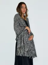 Chaleco tipo pashmina tejido en color blanco con detalles plateados y flecos en el borde inferior.