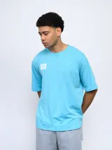 Remera celeste de corte holgado con cuello redondo y logo de Umbro estampado en el pecho.