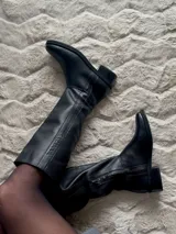 Bota alta de cuero vacuno color negro, con suela de goma, caña de 37cm y cierre lateral.