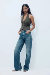 Top de cuello halter color verde oscuro, con escote pico, falso bolsillos de vivo en delantero y cinturón negro con hebilla metálica. Cierre frontal con cremallera oculta.