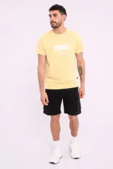 Remera mostaza de algodón con cuello redondo y estampado de una bicicleta con tablas de surf y el texto "Live Simply".