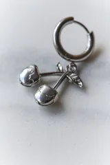 Par de aros plateados con forma de cerezas colgando de un aro pequeño.